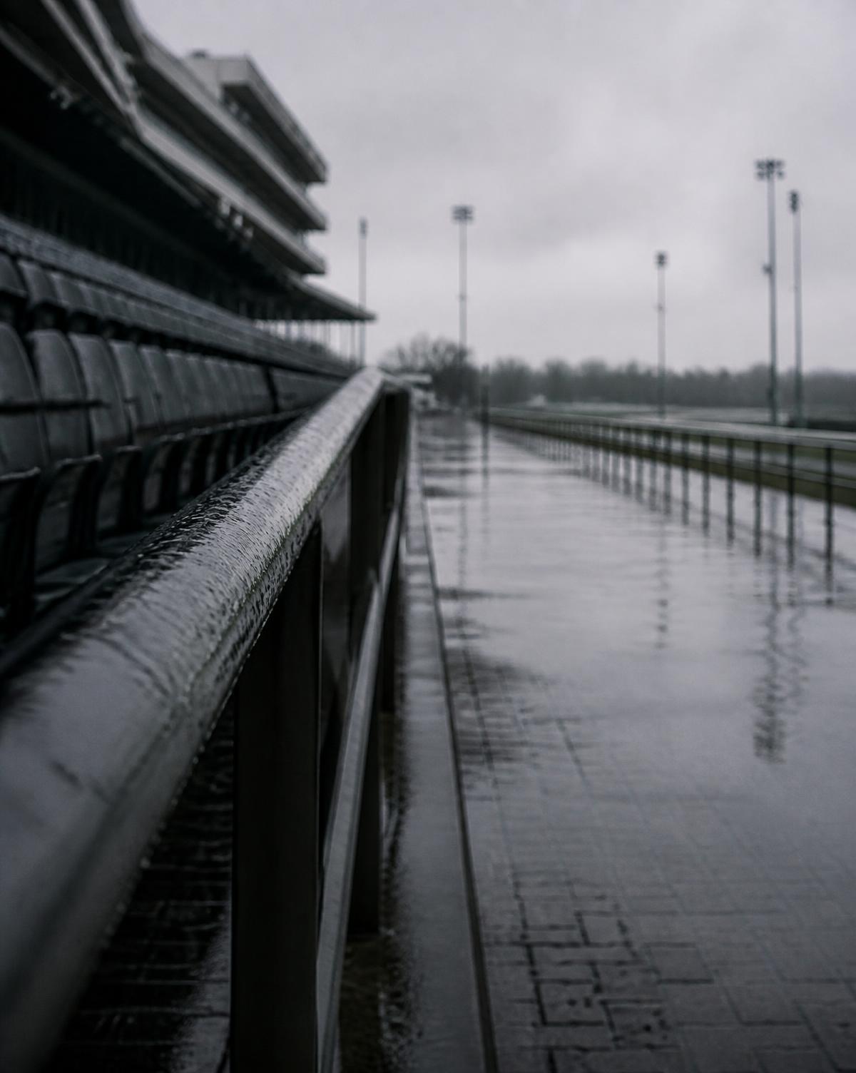 A horseman watching work from the training track rail